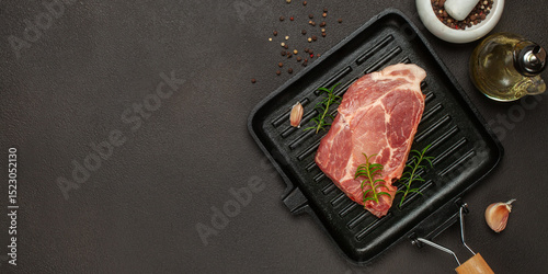Raw beef steak with spices on a dark board. Top view. Copy space