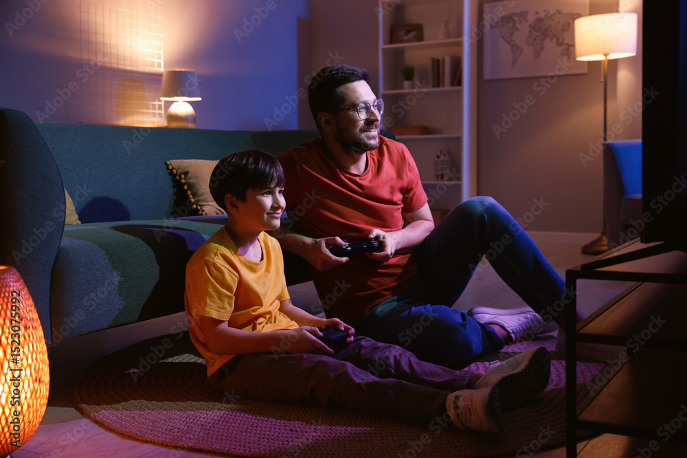 © New Africa - Happy father and his son playing video games on floor in living room at night