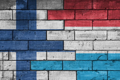 colourful painted big national flag of finland and flag of luxembourg on a massive old brick wall background. concept