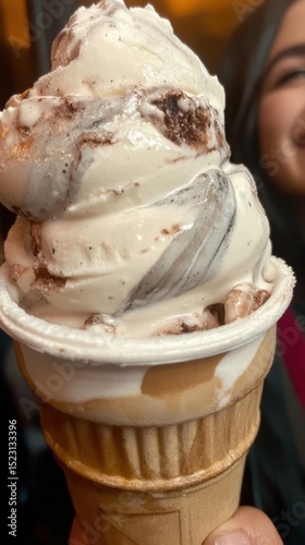 Delicious Vanilla Fudge Swirl Ice Cream Cone with Creamy Texture Being Held