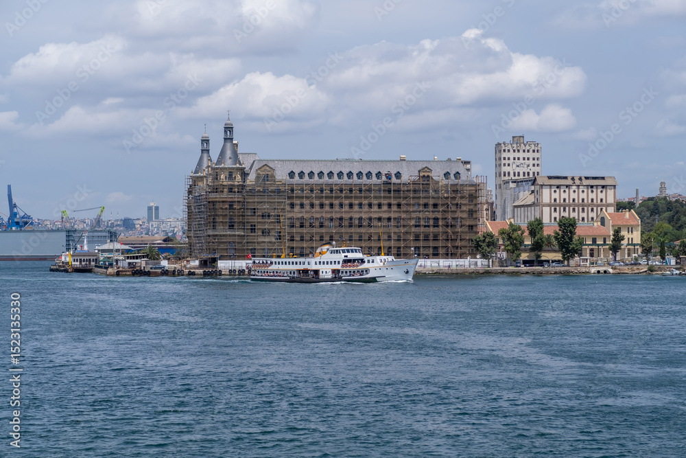 Fototapeta premium Bosphorus waterfront with restoration work on historical buildings and a ferry cruising in sunny weather