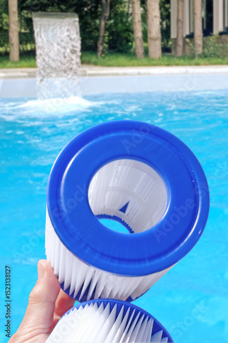 Reusable pool cartridge filter on a pool backdrop. Cleaning and maintenance home pool, water filter replacement.
