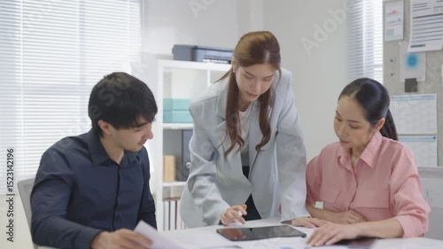 A group of Asian business professionals gathers in a modern office for a focused financial consultation, discussing strategies and analyzing performance data to drive success and business growth