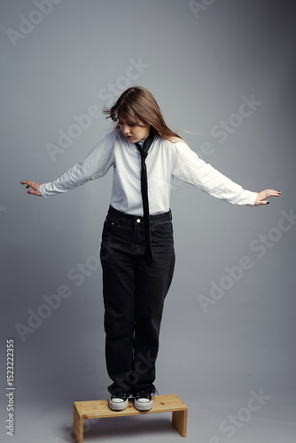Young Woman Balancing on Bench, Hair Blowing, Looking Down