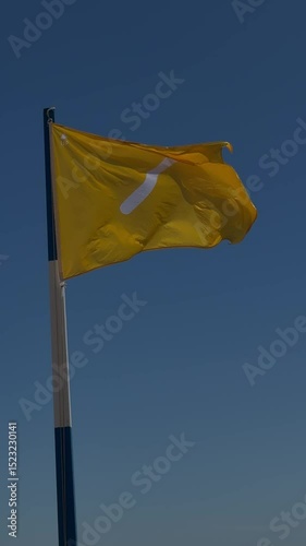 Yellow flag with white diagonal stripe waving in the wind