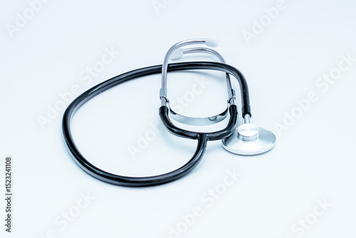 Black stethoscope resting on a white surface, representing medical care, auscultation, and the diagnosis of health conditions