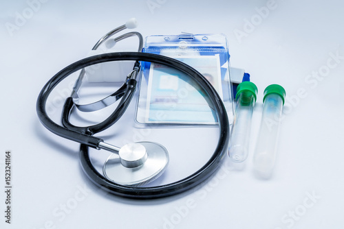 Medical instruments and doctor's badge lying on a white surface, suggesting healthcare and medical check up