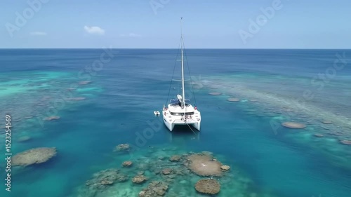 Pristine white catamaran floating near vibrant coral reef, anchored in crystal-clear turquoise waters of tropical seascape 
