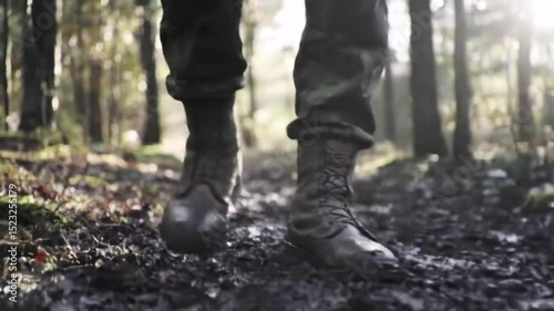 Soldier trudges through muddy terrain during training exercises in a dense forest