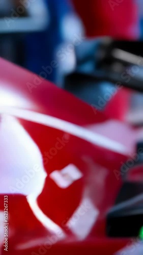 Close-up view of a single-seater racing car with driver in helmet ready to race, highlighting aerodynamic design and glossy red paint.