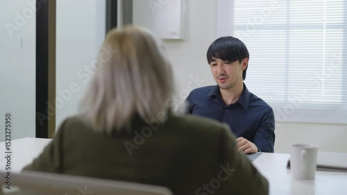 A confident and happy businessman participates in a professional job interview with a human resource manager in a modern corporate office. With a poised smile and clear communication, the male job