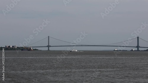 new york city ferry white boat passing in front of Verrazzano-Narrows Bridge between brooklyn and staten island nyc waterway harbor waterfront commute travel rockaway