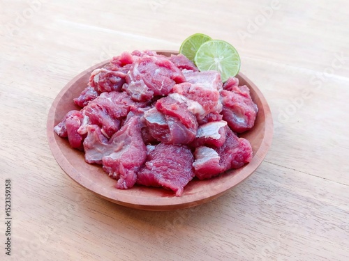 raw goat meat served with lime on a wooden plate on a wooden background.