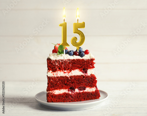 Canvas Print Piece of cake with berries and burning number shaped candles on white wooden table