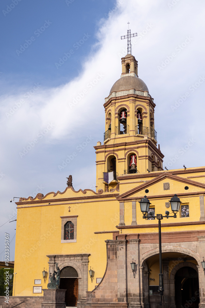 Fototapeta premium Cúpula del Santuario y Convento de la Santa Cruz de los Milagros, Queretaro, México, Religión Católica, cruz cristiana en la punta de campanario con arcos, amarillo colonial
