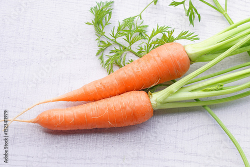 Organic mini carrots with leaves isolated on white wood background.