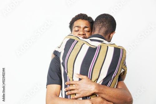 Embracing black men share a heartfelt moment, showcasing love, unity, and connection in a joyful atmosphere. The composition highlights their emotional bond beautifully. photo