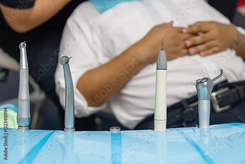 Close-up of professional dental tools on a sterile tray in a modern dental clinic. Equipment includes turbine handpieces and ultrasonic scaler in clean white background.