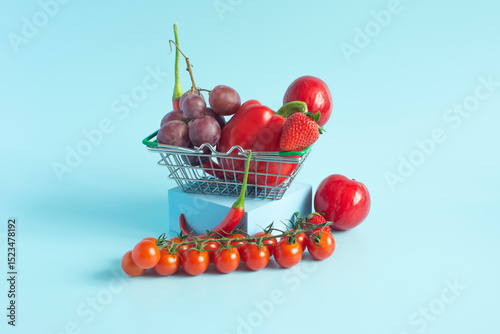 Red vegetables fruits and berries sweet peppers, hot peppers and cherry tomatoes strawberries grapes in a basket close-up on a light background