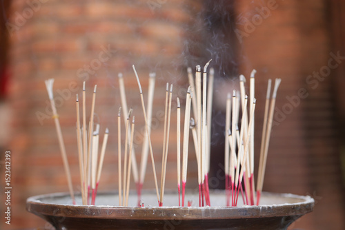 Incense sticks are stuck in a pot with smoke rising from above. Incense sticks that are lit to worship the sacred objects are placed in the incense pot.