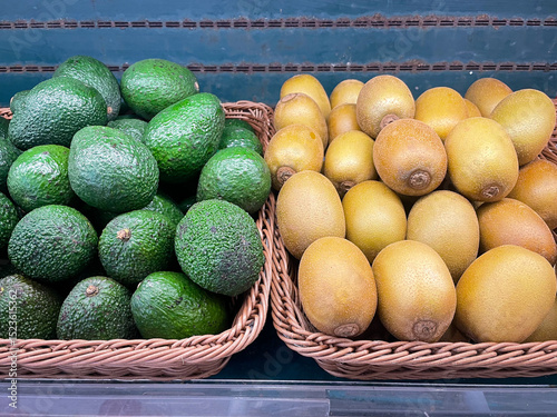Fresh organic Avocados and Golden kiwi in basket for selling in the supermarket.