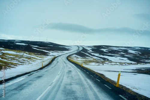 Road trip with uphill road landscape in winter at Iceland. Asphalt road with sideways full of snow