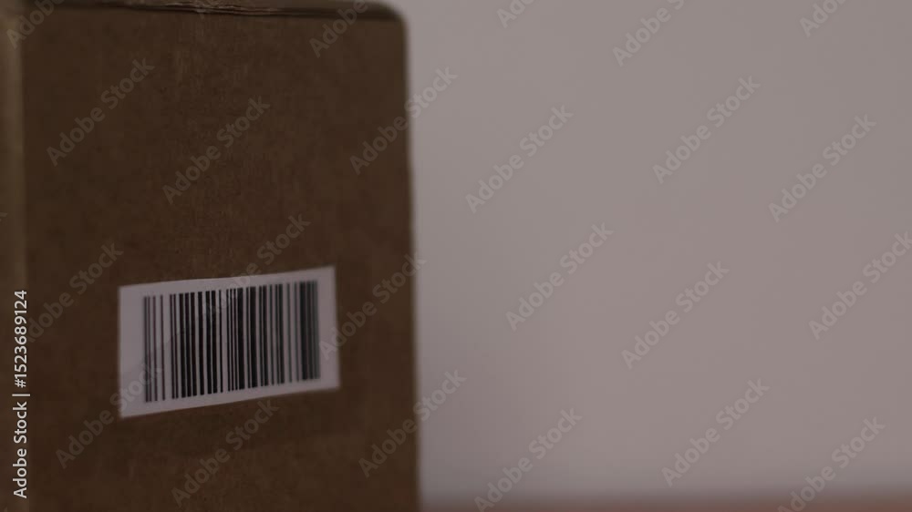close-up of a parcel in a cardboard box with a barcode being scanned by a laser beam from a barcode scanner, logistics center or parcel pick-up point
