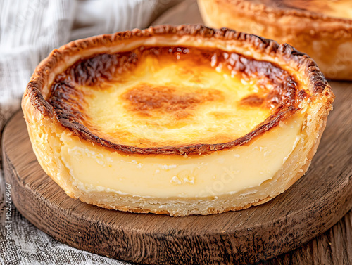 Delicious custard tart with golden crust and creamy filling on wooden surface.