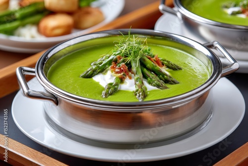 Delicious cream of asparagus soup garnished with fresh asparagus, cream and crispy bacon