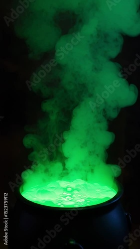 Halloween cauldron with glowing green potion and spooky smoke. Halloween magic brewing in black  witch's pot with green liquid.