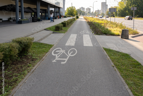 Fotografia A dedicated two-way bicycle path with road markings runs alongside a busy street