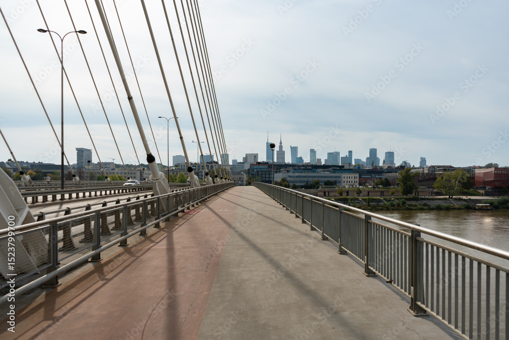Fototapeta premium A view of the Warsaw skyline from the pedestrian and bicycle path on the Swietokrzyski Bridge. This modern bridge with a dedicated bike lane crosses the Vistula River.