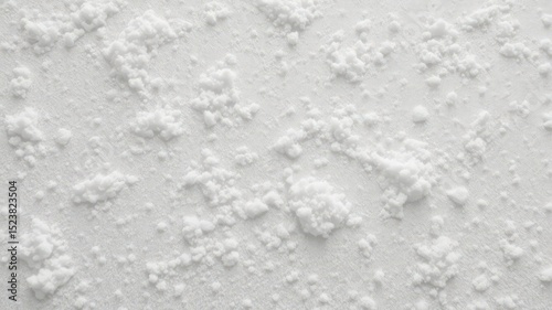 An array of bright white fluffy crystals and fine particulate covering and adhering to a simple textured surface