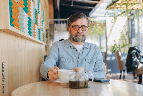 Foto Senior Man Drinking Tea in a Modern Cafe