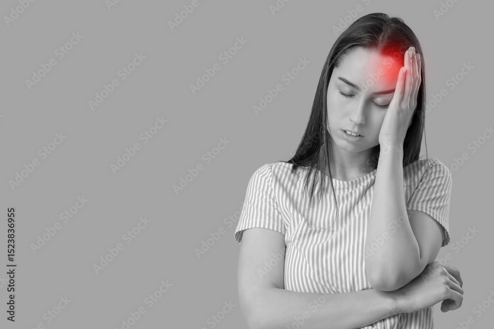 Fototapeta premium Tired young woman suffering from headache on grey background