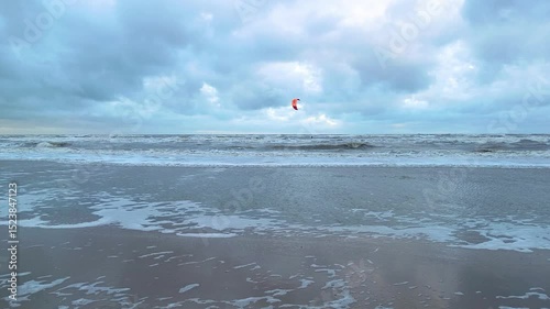 Zandvoort sea beach in the morning with crashing waves and kitesurfing or kiteboarding in the sea.