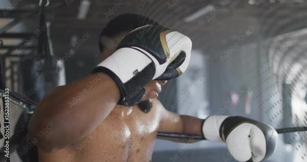 Boxer bracing on ring ropes, reacting to bag swinging behind mesh ...