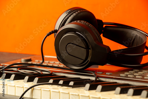 Headphones on electronic piano keyboard Synthesizer with orange background