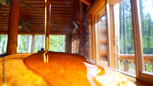 Pancakes stack on plate, syrup poured. Close-up of sandwich with syrup. Person seen through window in background. photo