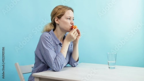 woman Eating Fresh nectarine on the blue background, healthy snacks and fresh food