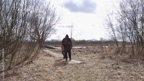 Nature lovers walking in spring field near lake shore.