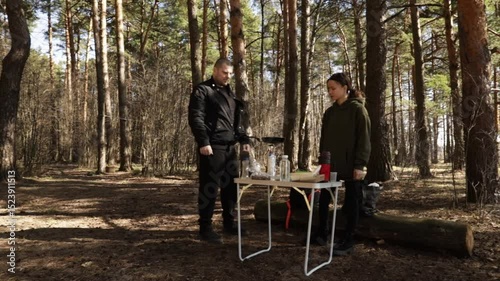 forest lifestyle scene of campers making breakfast on a portable burner while surrounded by dense trees and early spring light, evoking warmth, nature