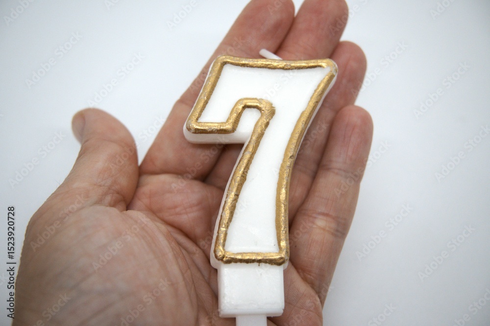 Obraz premium Number 7 birthday candle close up with white background.