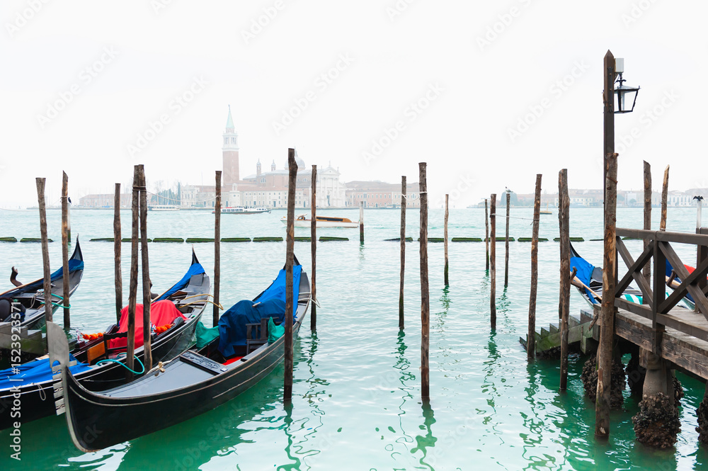Fototapeta premium Gondolas on the Grand canal at foggy sunset in Venice, Italy. San Giorgio Maggiore Cathedral in the background.