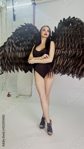 Elegant woman showcasing elaborate winged costume in studio setting