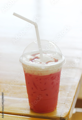 Pink iced milk on a wooden table at cafe