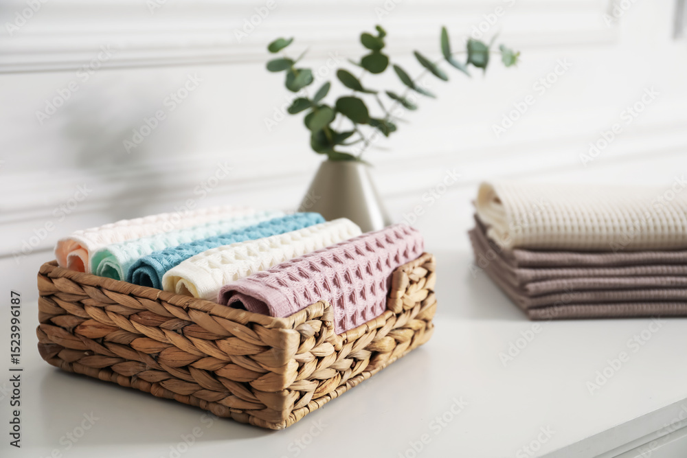 Obraz premium Clean waffle towels and vase with branches on white dresser in bathroom, closeup