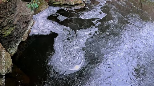 White foam swirls on the surface of the water near a waterfall Bushkill Falls, Pennsylvania, USA
