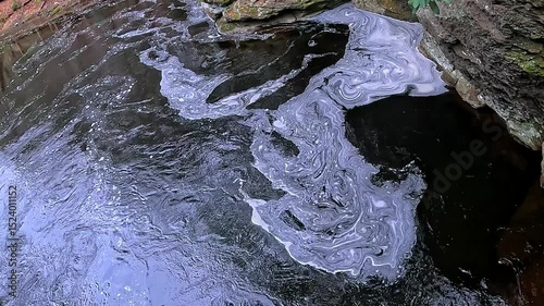 White foam swirls on the surface of the water near a waterfall Bushkill Falls, Pennsylvania, USA