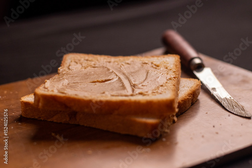 Photo of, A slice of artisanal sourdough bread with a thick spread of creamy peanut butter, Minimalist kitchen counter setting
